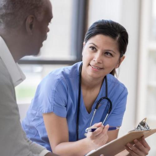 A doctor holding a chart talking to a patient