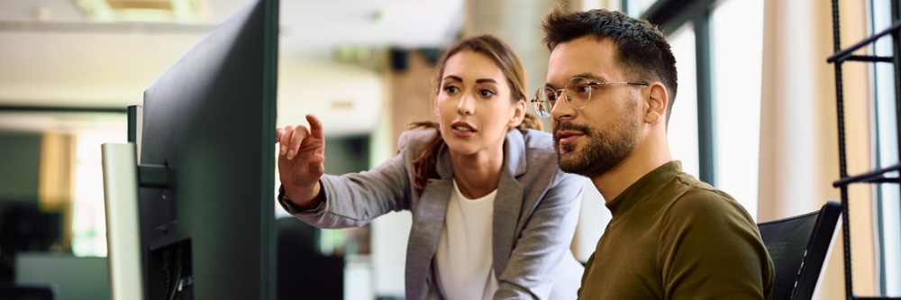 Woman pointing at computer screen with a man sitting beside her