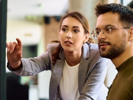 Woman pointing at computer screen with a man sitting beside her